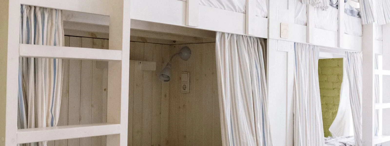 A modern dorm room with bunk beds, privacy curtains, and built-in under-bed storage